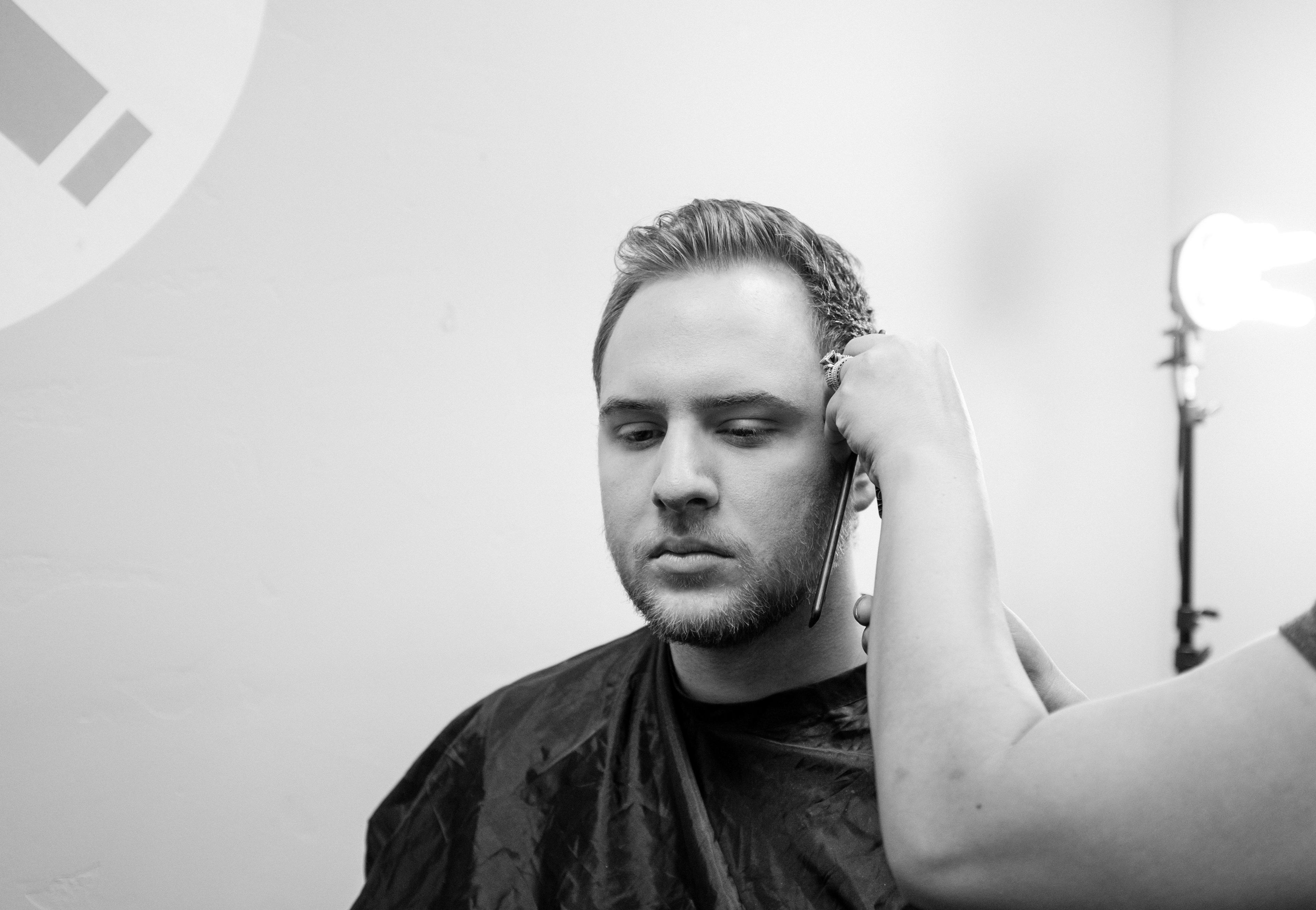 a man getting his hair cut by a woman