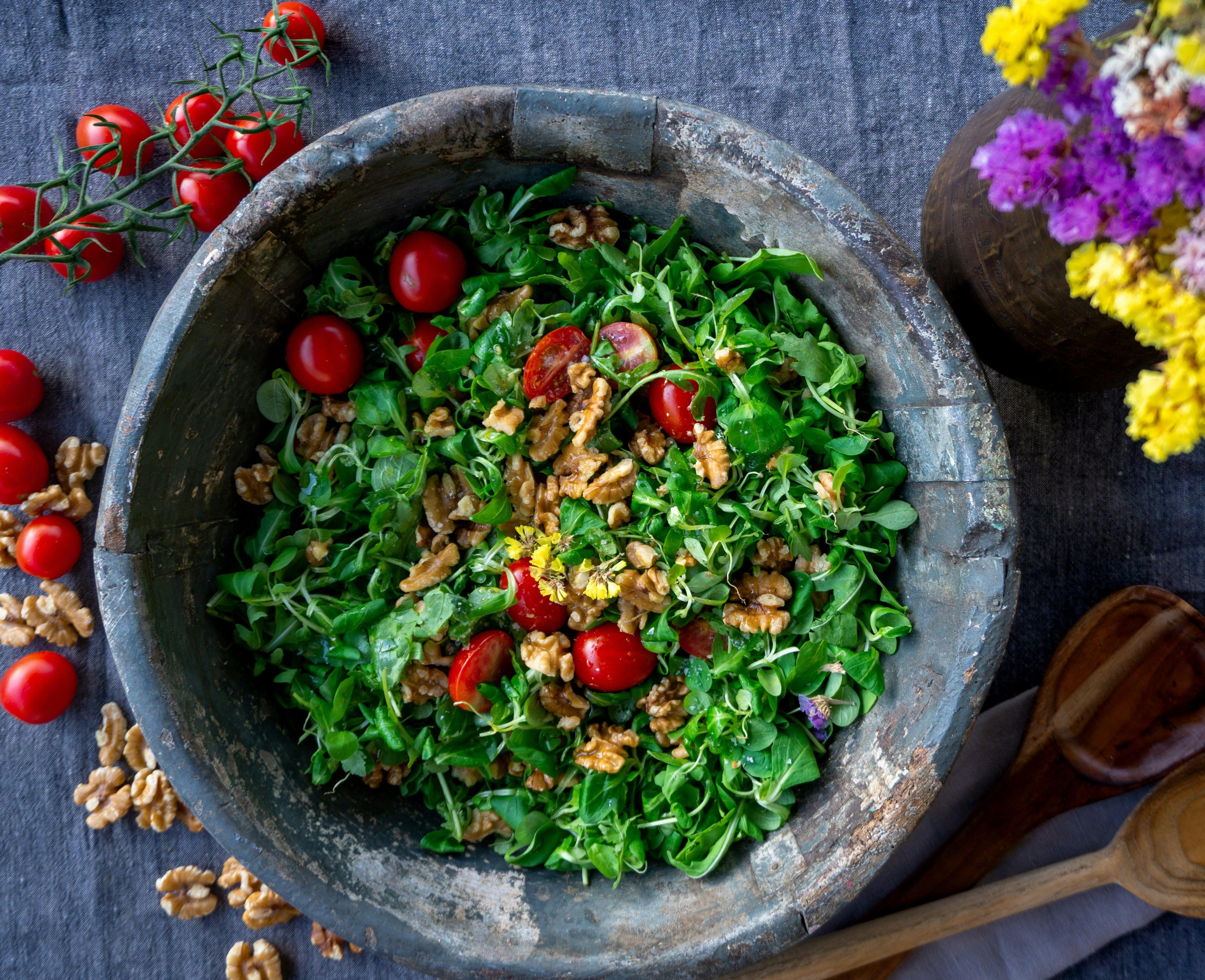 a bowl of salad with cherry tomatoes and walnuts