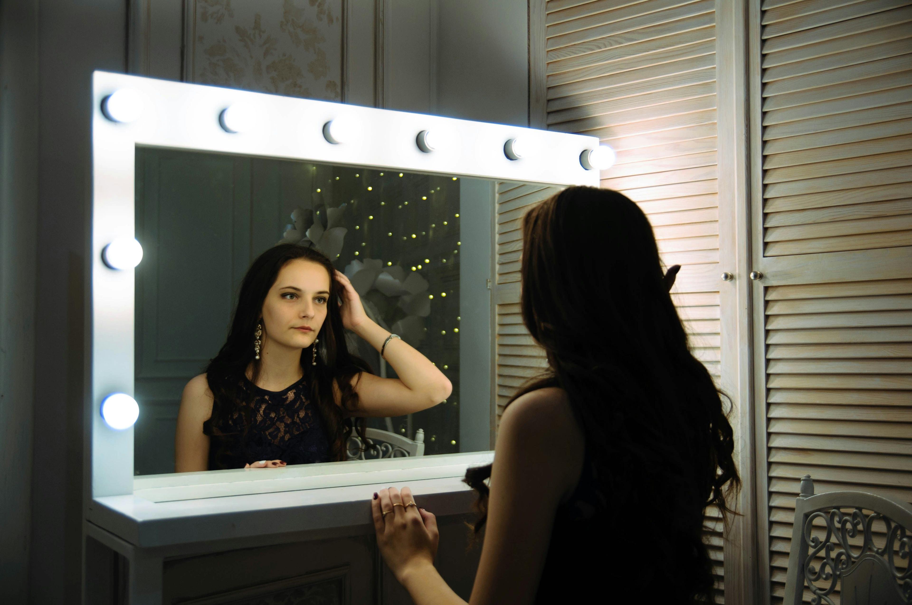 a woman standing in front of a mirror brushing her hair