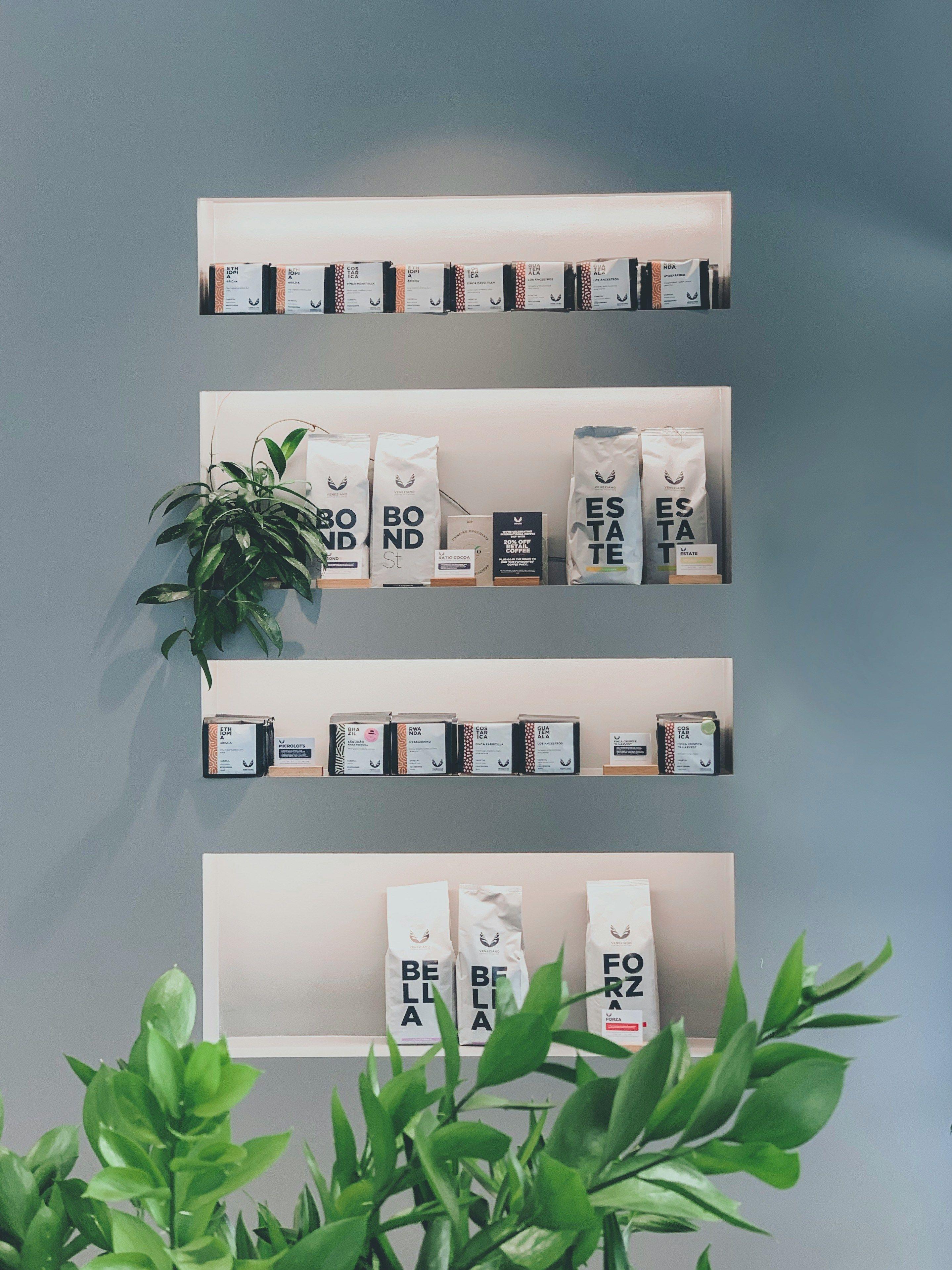 a shelf with coffee bags and a potted plant