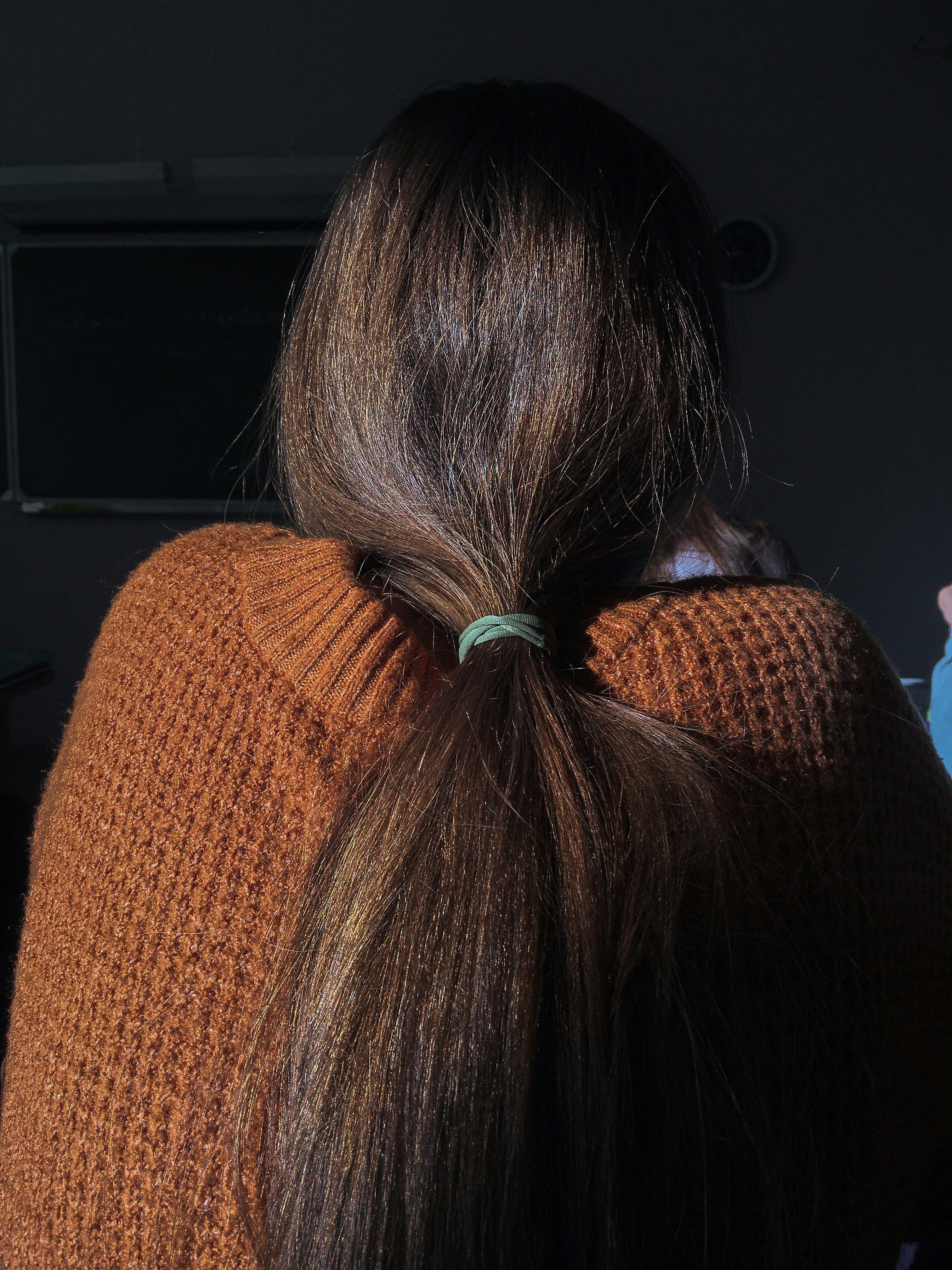 a woman with a ponytail is wearing a sweater