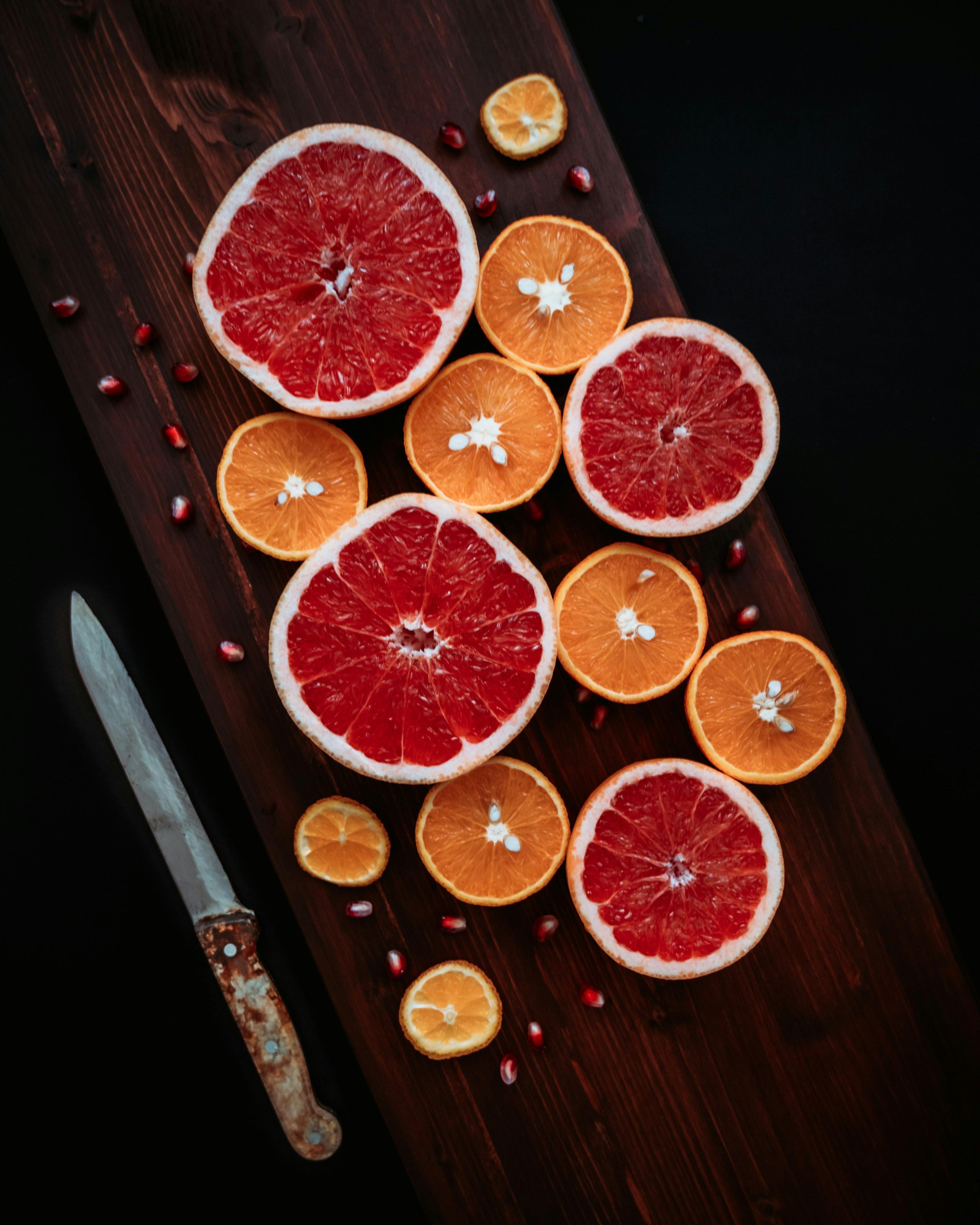 a cutting board topped with sliced oranges and a knife